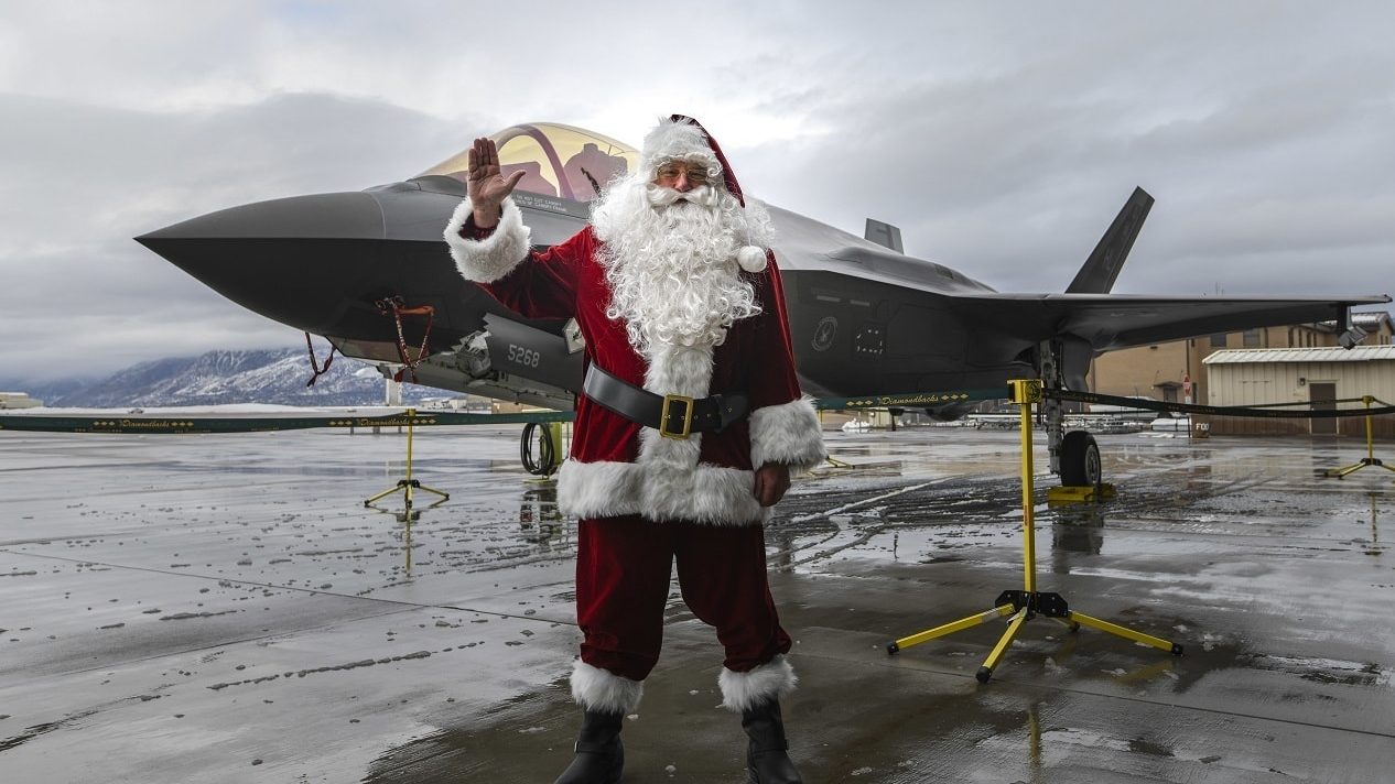 Père Noël saluant devant un chasseur F-35