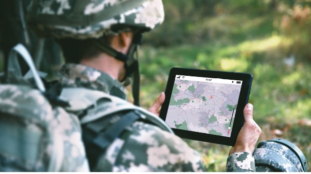 Militaire regardant une tablette avec une carte et un positionnement GPS dessus